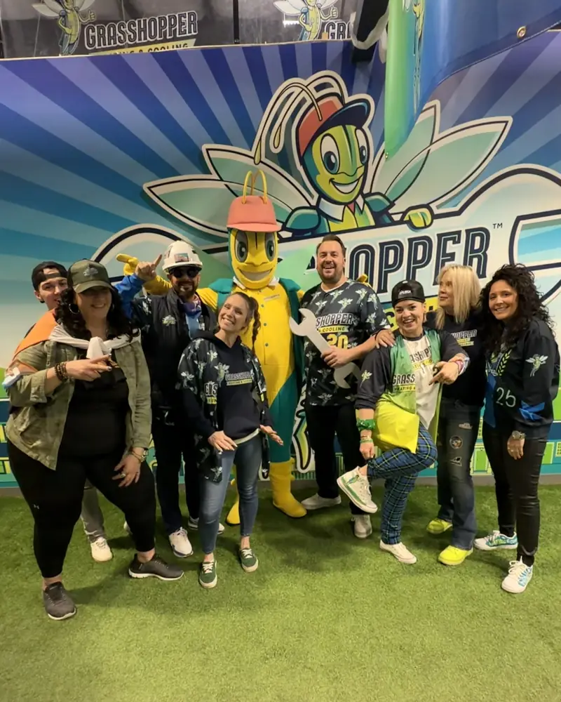 The Grasshopper team with the Grasshopper mascot in front of the mural